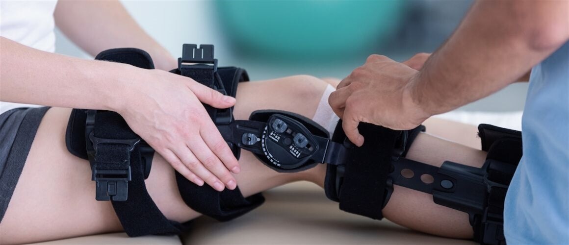 Image of physical therapist helping woman with leg brace.