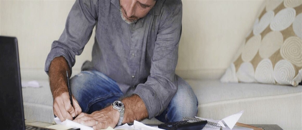 Man sitting on couch, paying credit card bills.