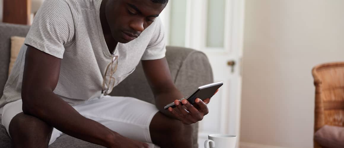 Man sitting on couch, paying credit card bills.