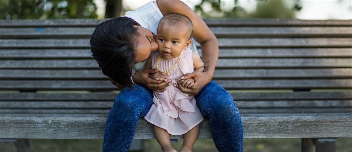Image of woman holding child on park bench.