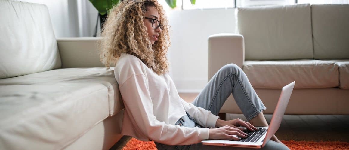 Image of woman sitting, reviewing loan offers on computer.