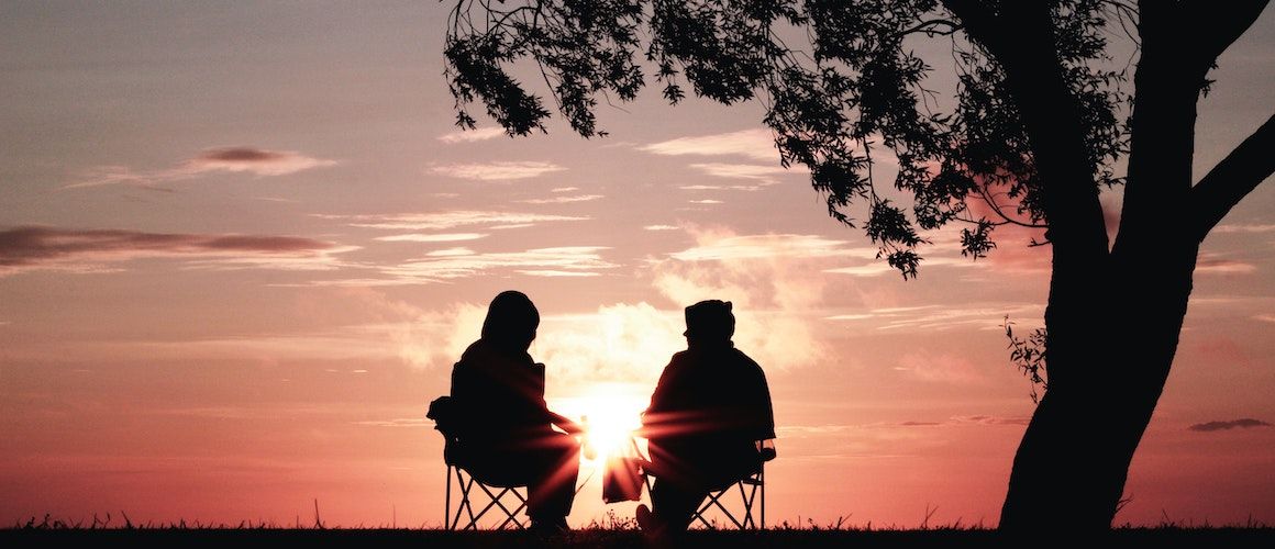 Silhouette image of couple sitting and enjoying sunset.