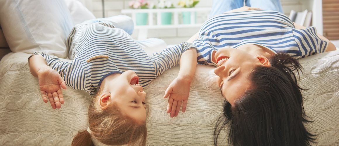 Image of happy mom and child laying on bed.