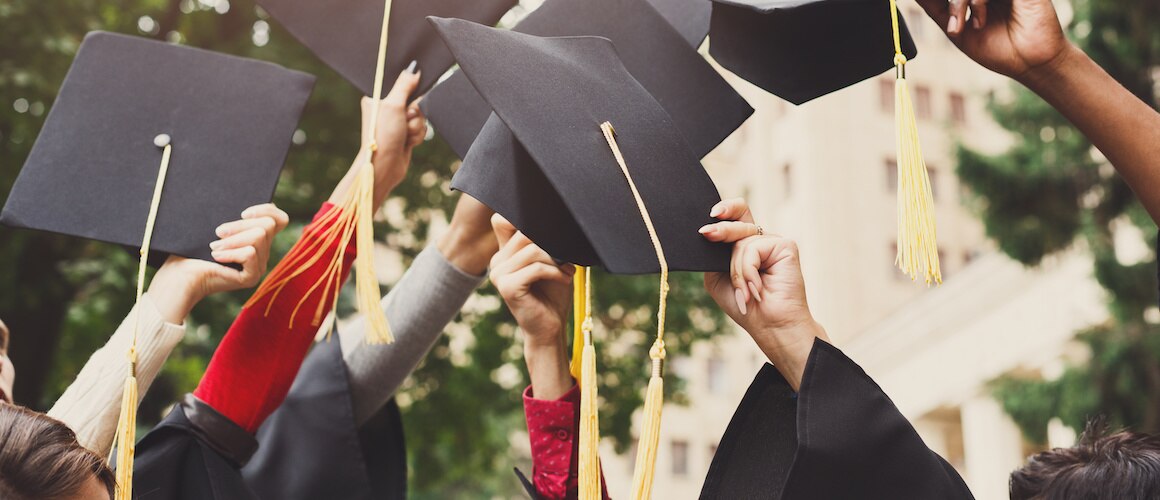 Image of college graduates throwing graduation caps into the air.