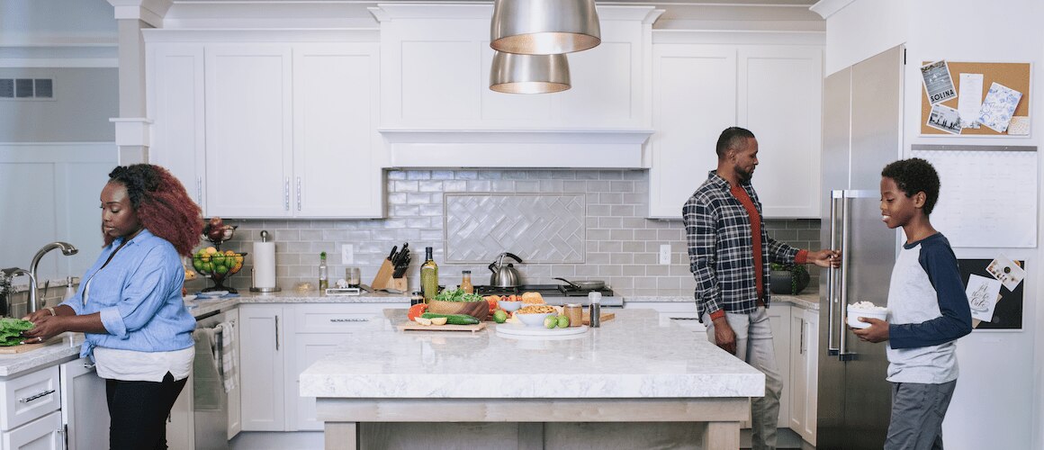 Image of family in white, sustainable kitchen preparing a meal.