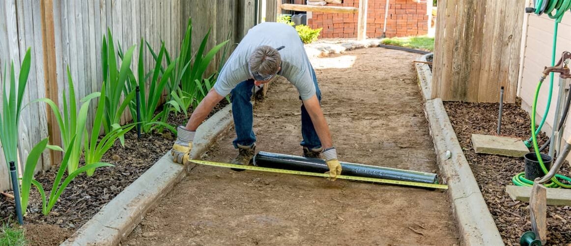 Image of man measuring materials for outdoor home project.