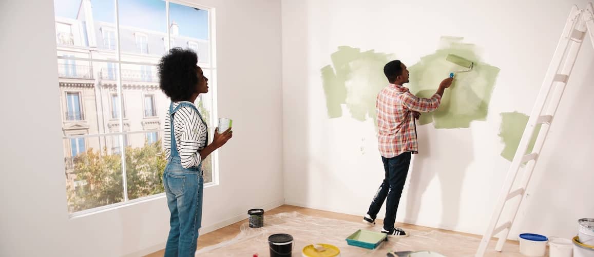 Image of African American couple painting their apartment walls green.
