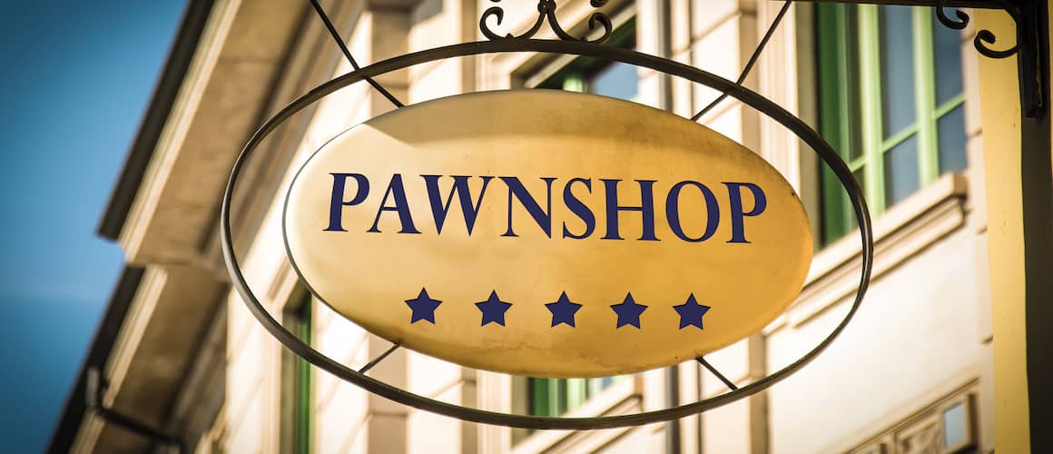 Pawnshop sign hanging in front of historic building.