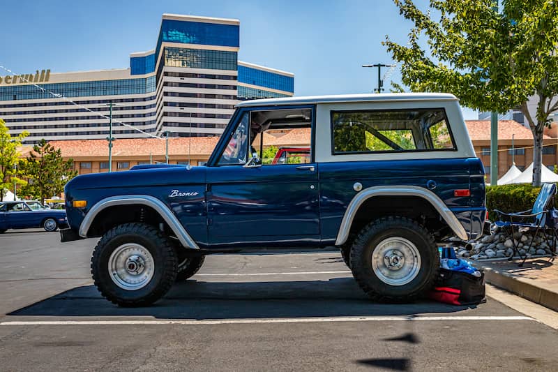 Side view of a dark blue Ford Bronco parked in a parking lot.