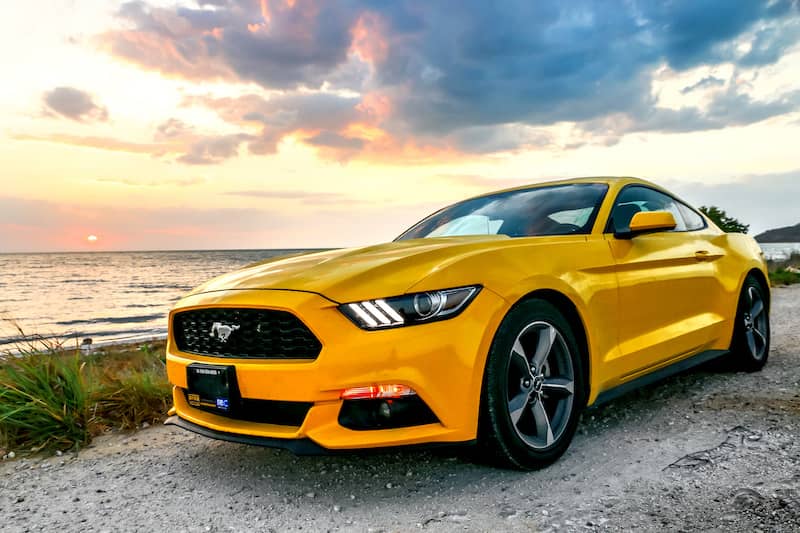 Yellow Ford Mustang parked on road.