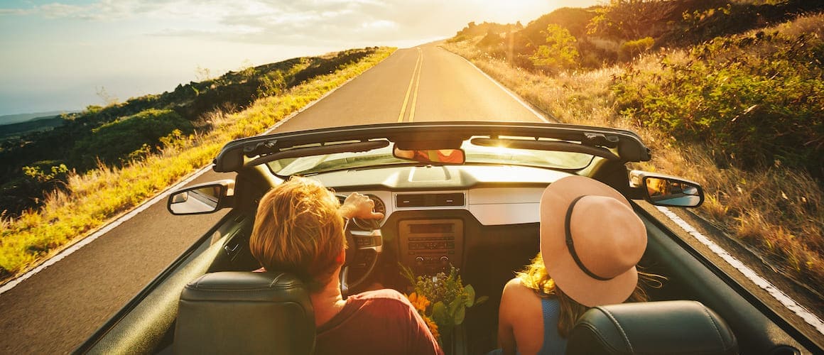 Friends in convertible with top down on Summer road trip.