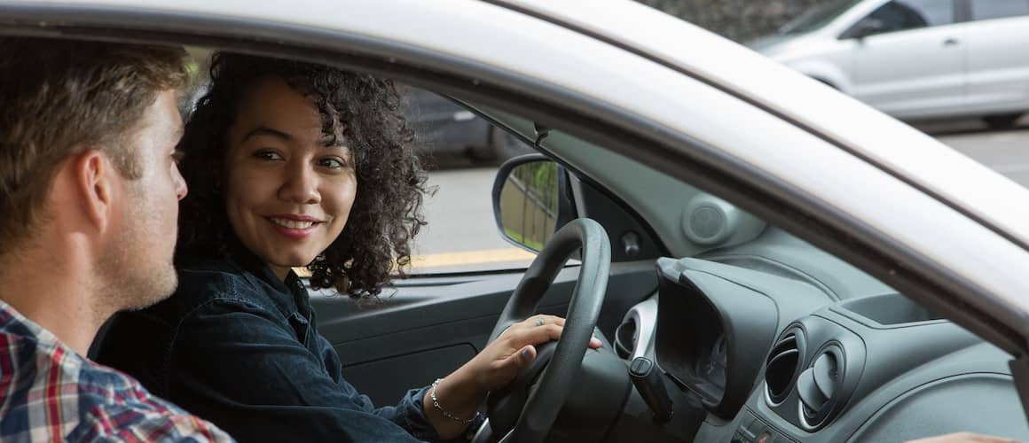 Couple in a car driving and smiling at each other.