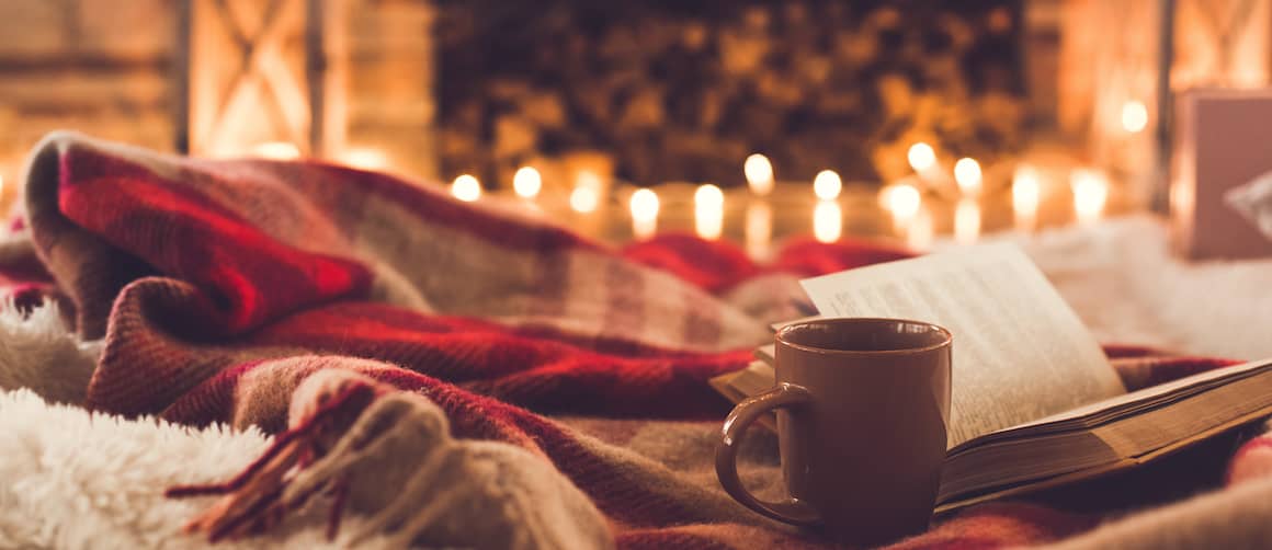 Blanket and coffee mug by a fireplace.