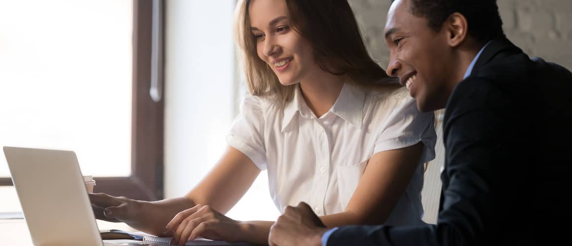Man and woman dressed in business casual attire looking at tablet in office.