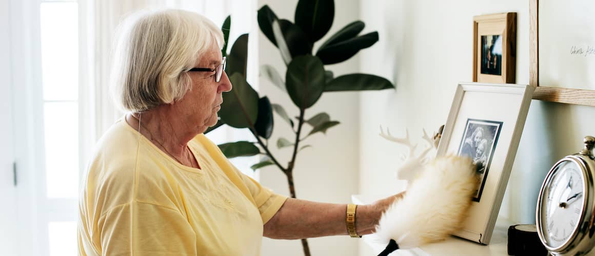 Older woman dusting her family photos.