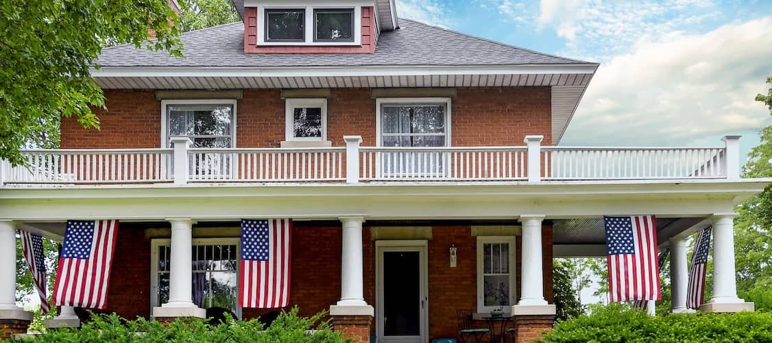 American flag decorations on front porch of old brick home.