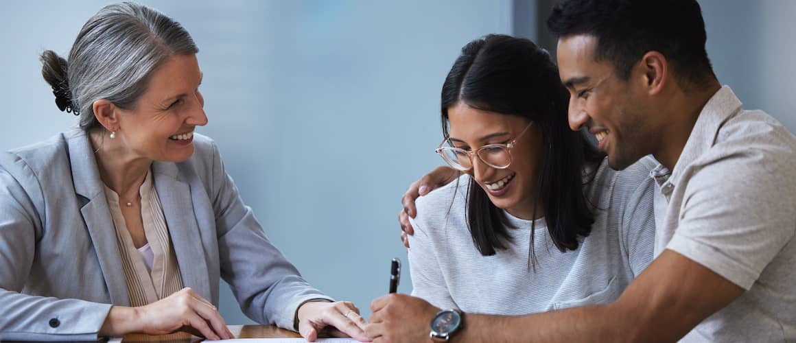 Young couple meeting with a financial consultant and signing paperwork.