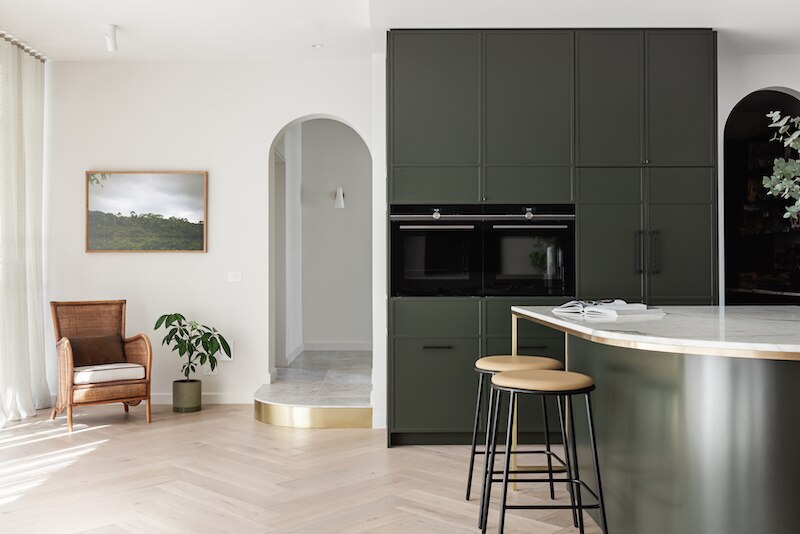 Contemporary Art Deco kitchen and adjacent room interior with rounded archway to hallway and rounded bar.