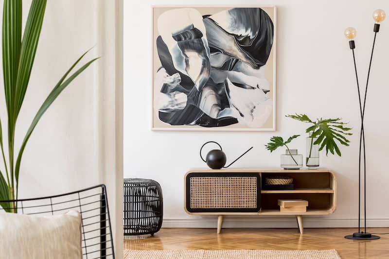Modern interior with throwback MCM elements featuring black and white abstract statement art and large houseplants.