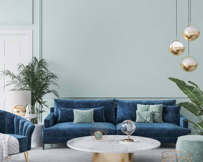 Living room with blue velvet couch and blue velvet chair with light blue painted wall.