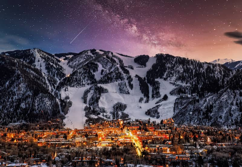 Aspen city at night backed by a large mountain.