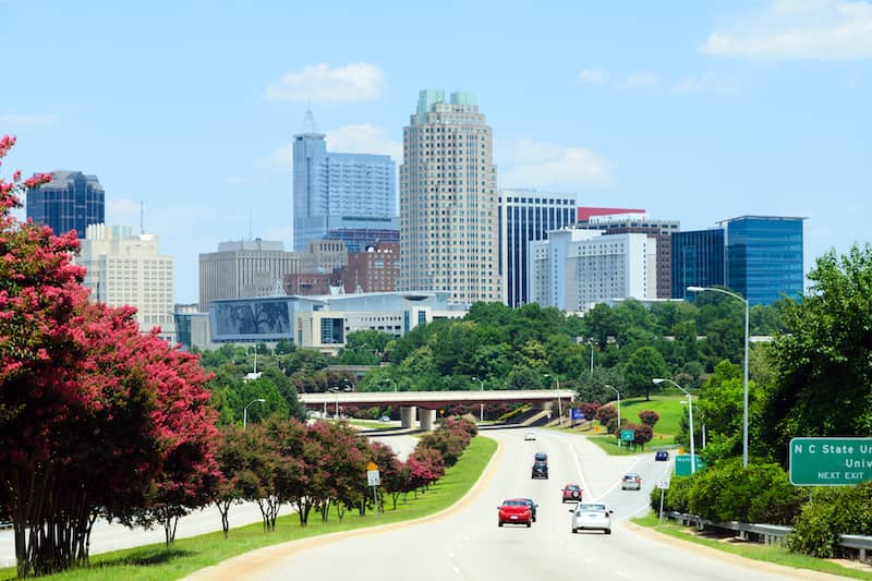 view of Raleigh driving towards downtown with red flowers along road