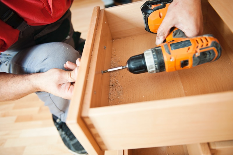 Person adding new hardware to cabinets and drawers.