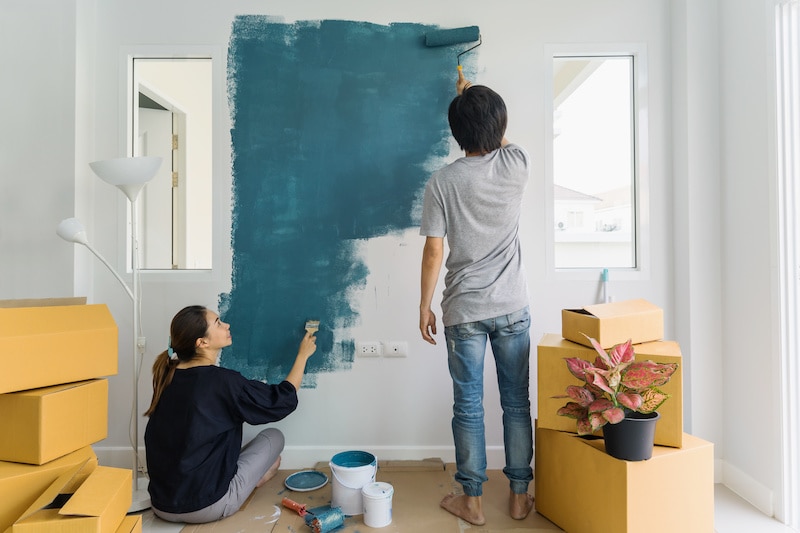 Young couple painting a wall together.
