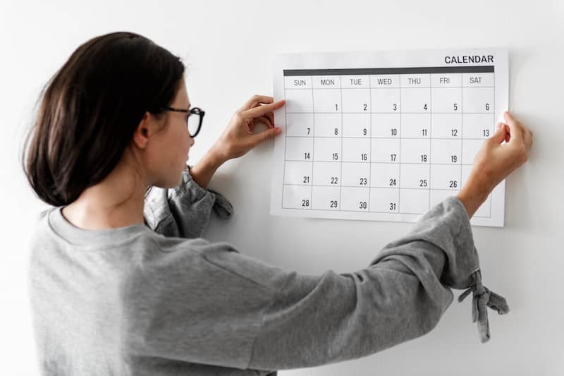 Woman mounting large paper month by month calendar to track her home improvement projects.