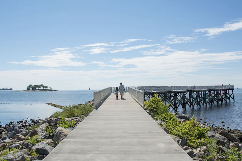Father and daughter walking along dock in Connecticut.