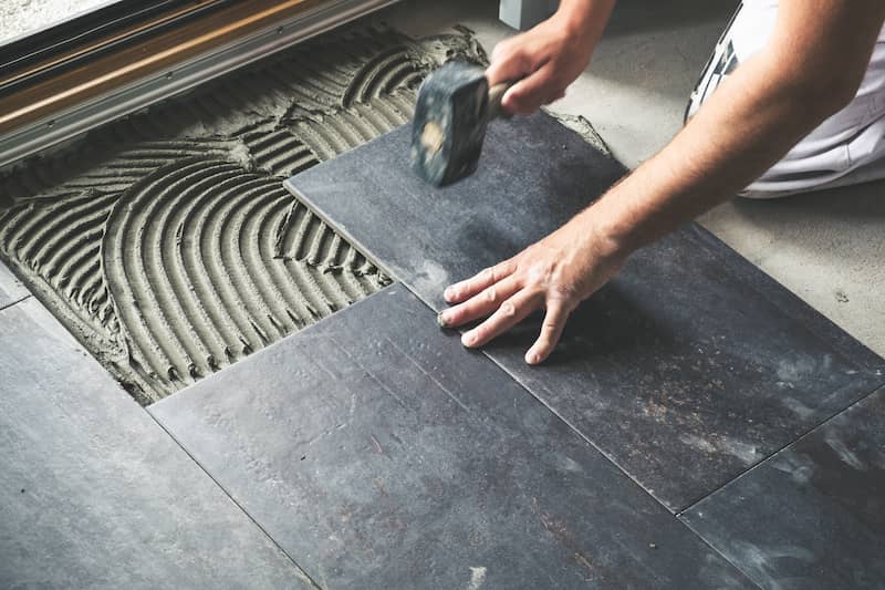 Man Laying Ceramic Tiles For Kitchen