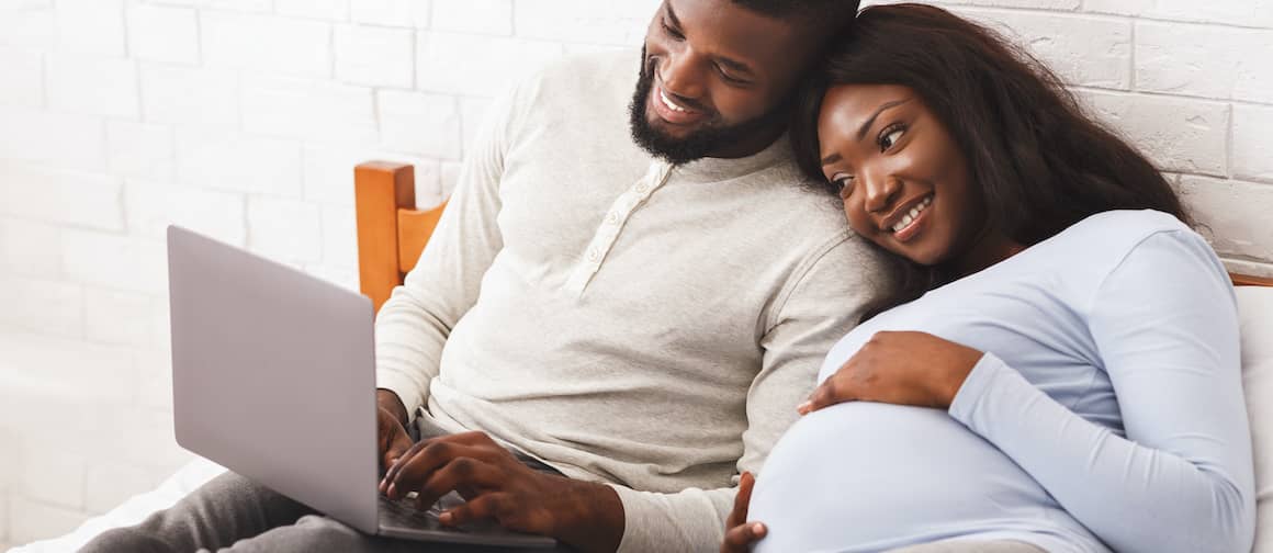 Expecting Couple Snuggling In Bed Looking For Starter Home