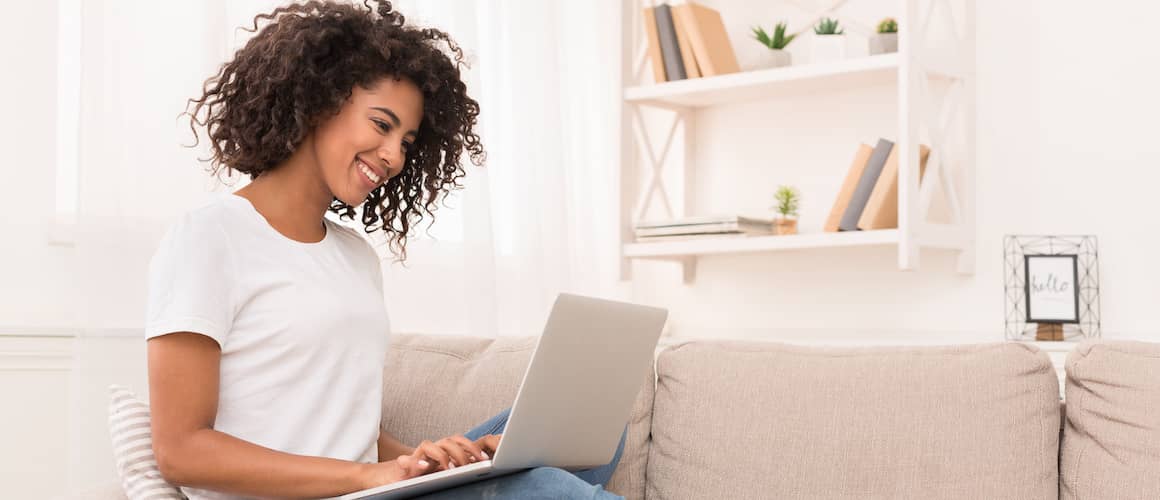 woman sitting on couch viewing laptop