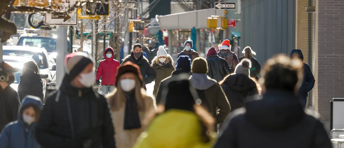 crowd of people walking down street with face masks
