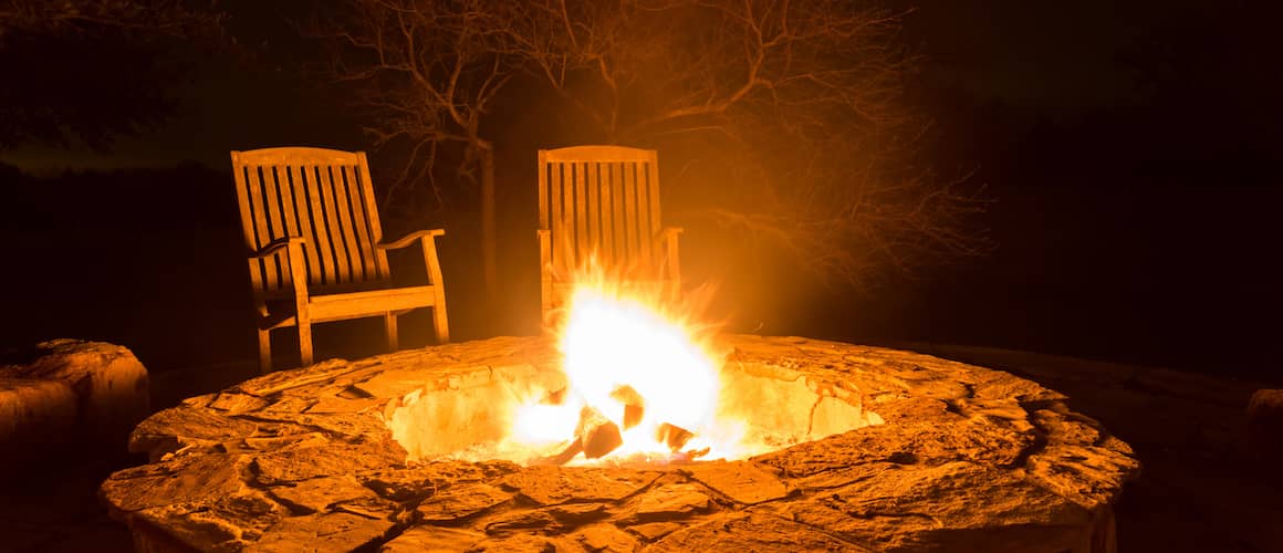 Fire pit in the dark, two rocking chairs at the back.