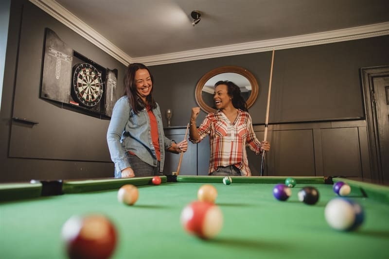 Friends playing billiards in basement.