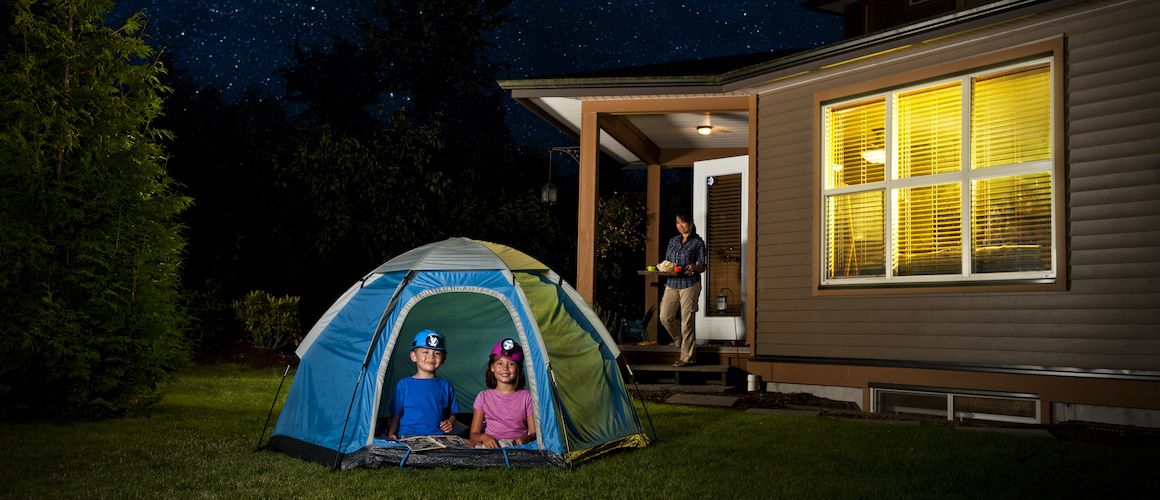 kids camping in the backyard while woman brings out tray of food
