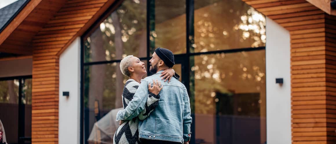 Couple in front of dream home they just made an offer on.