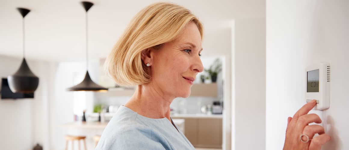 mature woman with short hair adjusting the thermostat