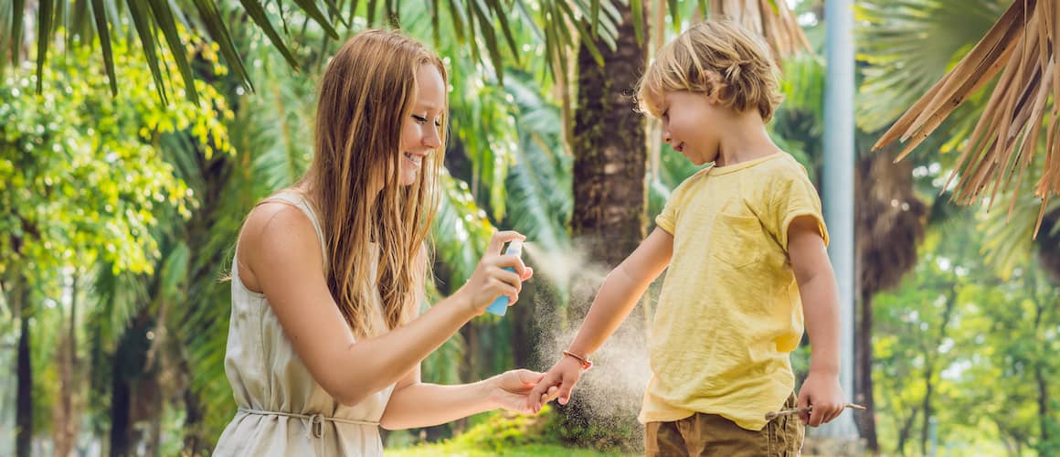 woman spraying child with mosquito repellant