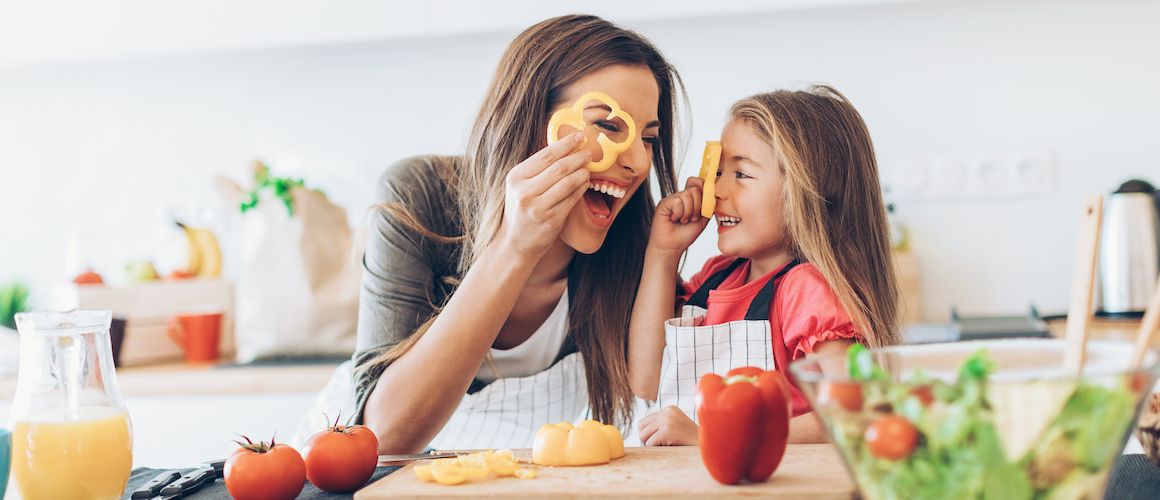 mother and daughter smiling while prepping vegetables