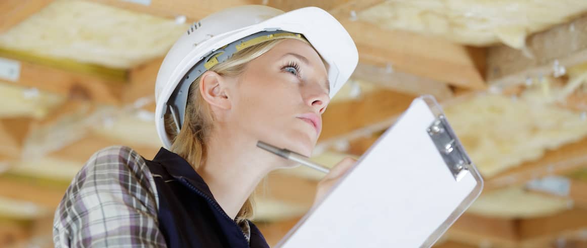 Female pest inspector with clipboard examines wood.