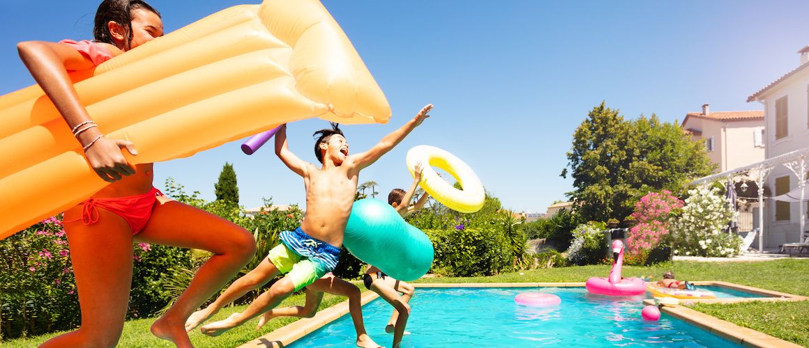 kids jumping into a pool with floaties