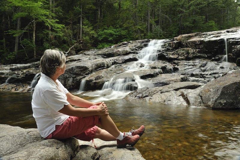 Senior woman relaxing by a waterfall in New Hampshire