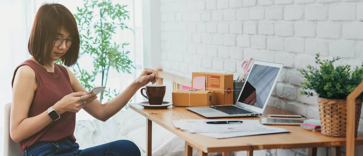 woman on phone near desk next to bed