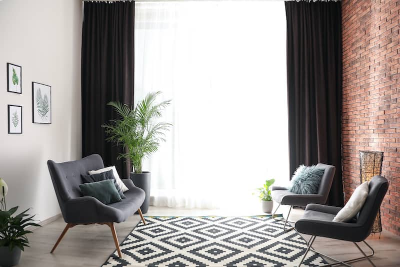 Black And White Geometric Rug Anchoring Chairs And Black Curtains In Room