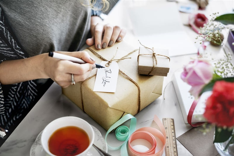 View of hands writing a thank you note on a package.
