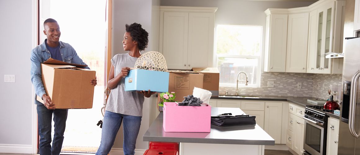 African American couple moving boxes into new kitchen.