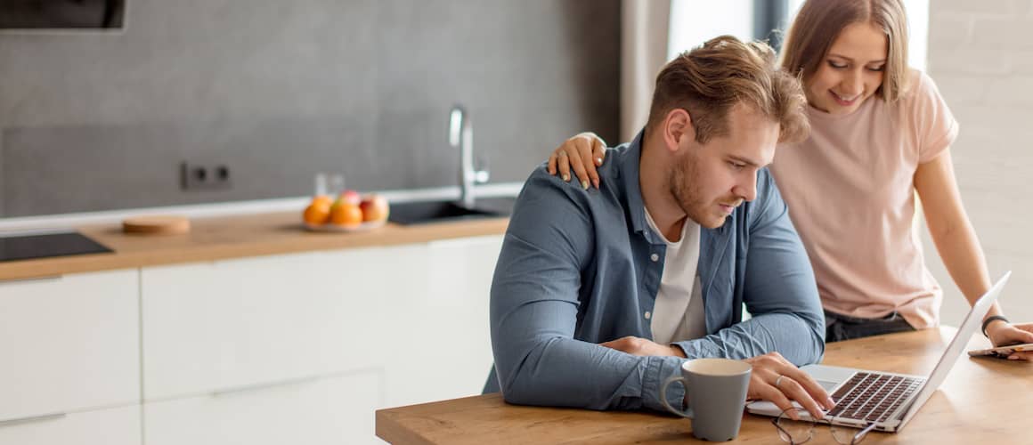 Couple In Kitchen With Laptop And Coffee