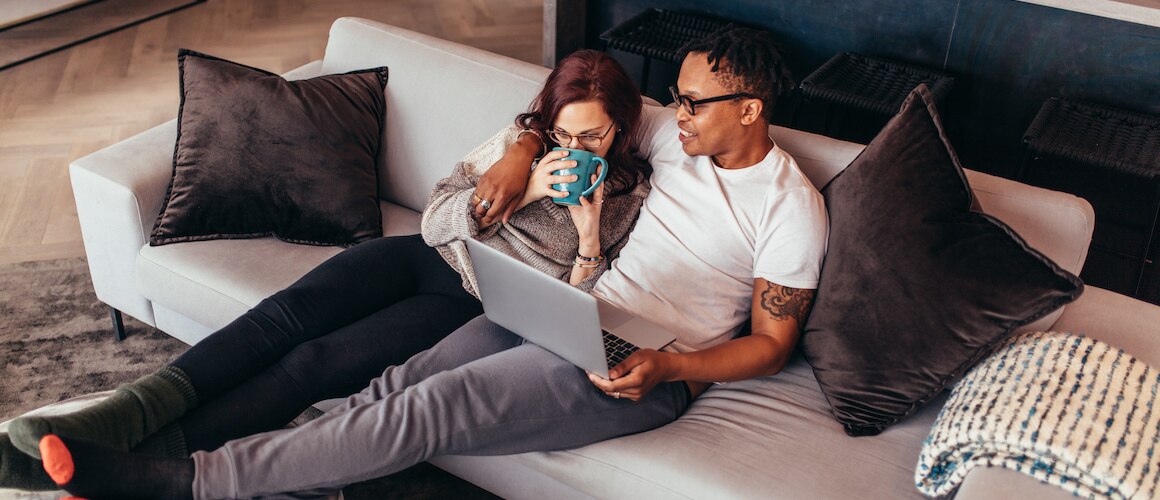 Couple relaxing on their couch looking at laptop.